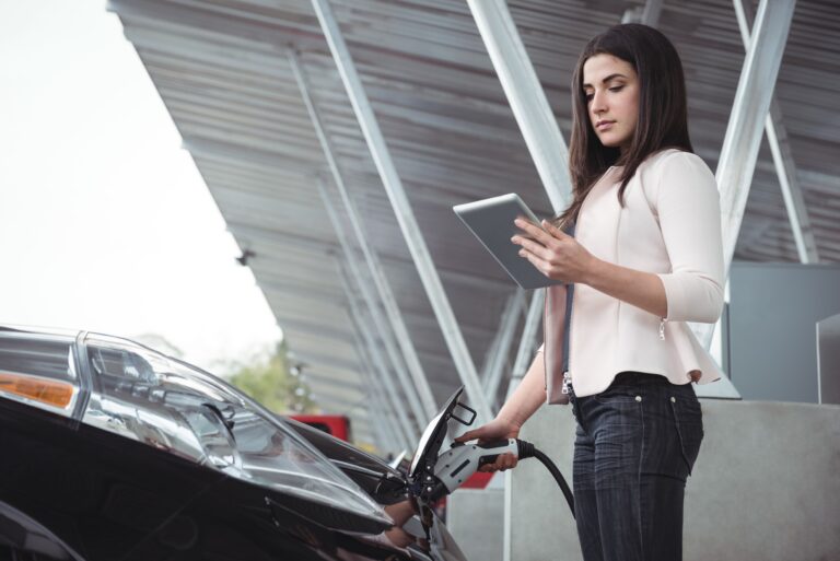 beautiful-woman-using-digital-tablet-while-charging-electric-car